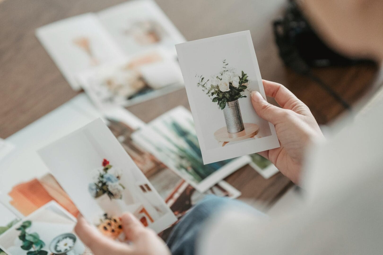 crop photographer choosing photos of flowers at table